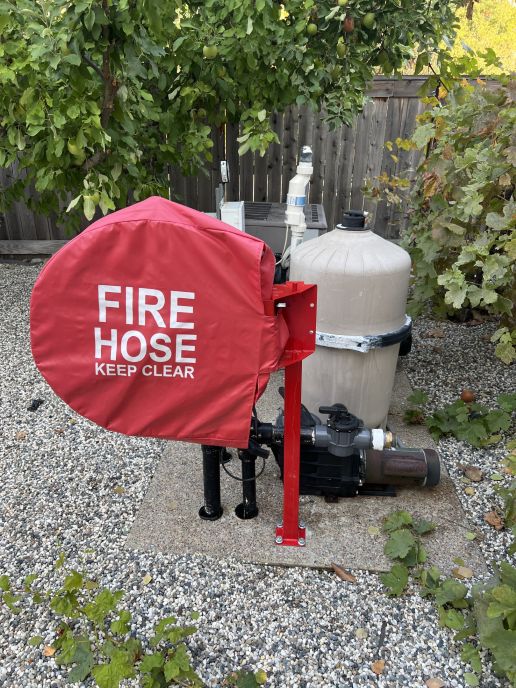 swimming pool fire hose reel and protective cover mounted on fence post