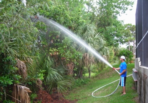 man spraying swimming pool fire hose system powered by existing pool motor